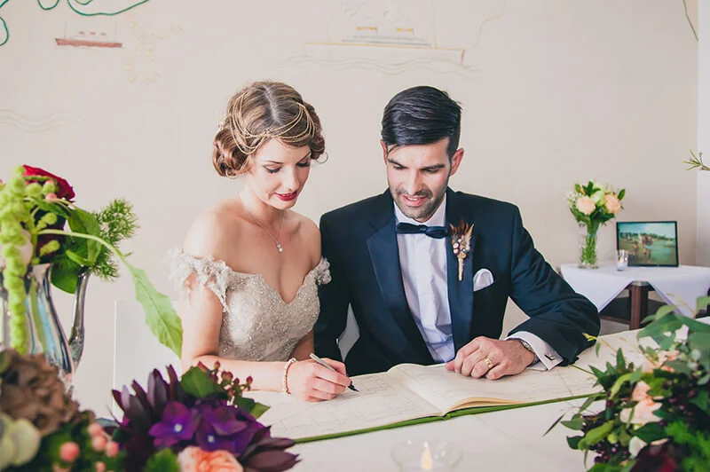 Bride and groom signing at a table with flowers
